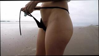 Watch the video about Walking on the beach micro bikini flash hairy pussy